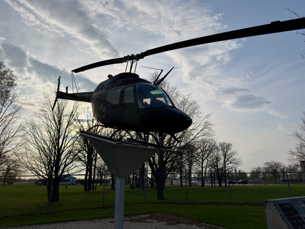 Air Force Heritage Air Park, Winnipeg: Planes, History and Coffee 64 Black helicopter mounted on a pole in a park, silhouetted against a cloudy sky with bare trees and grass below
