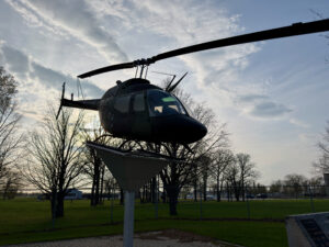 Air Force Heritage Air Park, Winnipeg: Planes, History and Coffee 67 Black helicopter mounted on a pole in a park, silhouetted against a cloudy sky with bare trees and grass below