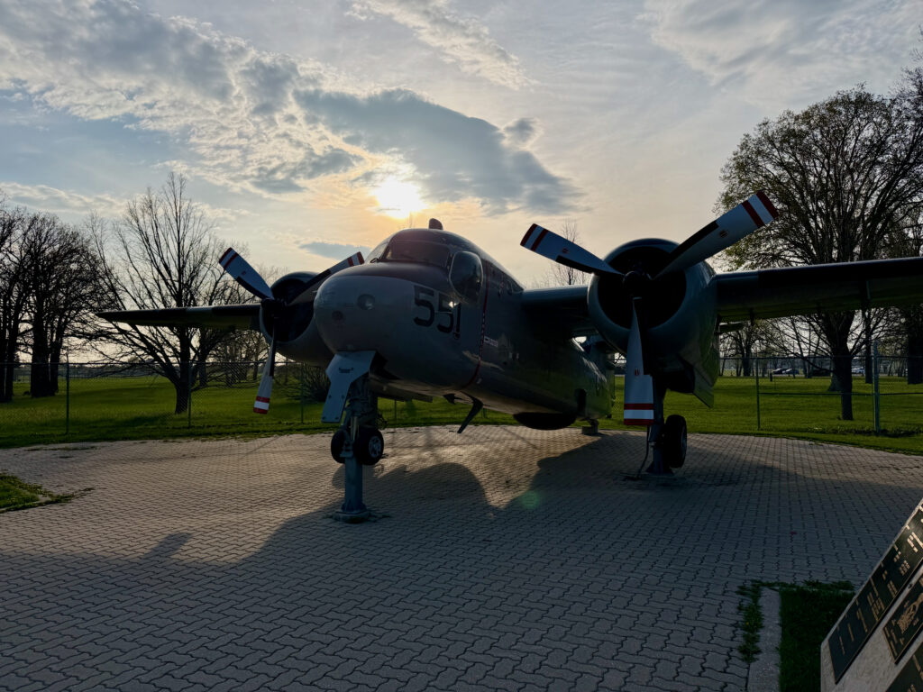 Air Force Heritage Air Park, Winnipeg: Planes, History and Coffee 49 Vintage twin-engine aircraft with number 51 on fuselage, displayed on brick platform in park setting with bare trees and cloudy sky