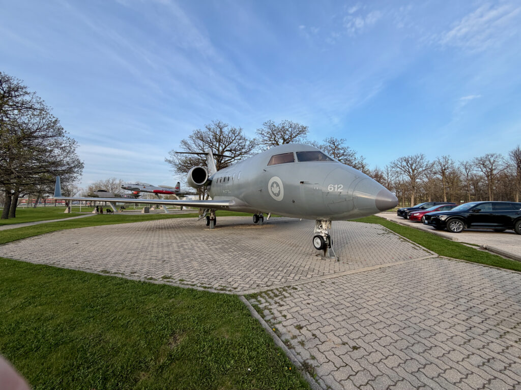 Air Force Heritage Air Park, Winnipeg: Planes, History and Coffee 31 Canadian Armed Forces Canadair CX-144 Challenger maritime patrol aircraft on static display, marked with tail number 612, parked on a brick plaza with bare trees and vehicles in the background