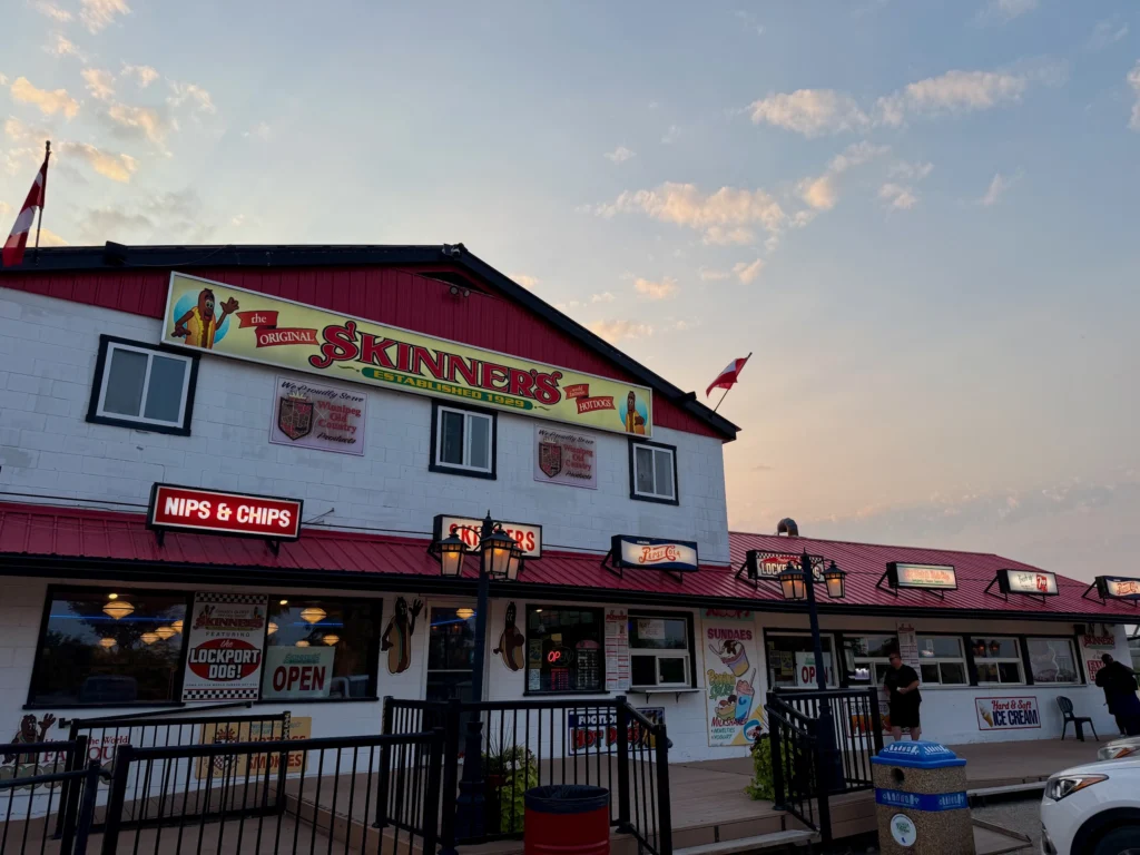 The Original Skinners restaurant exterior with red and white building, Nips & Chips signage, and Canadian flags at dusk