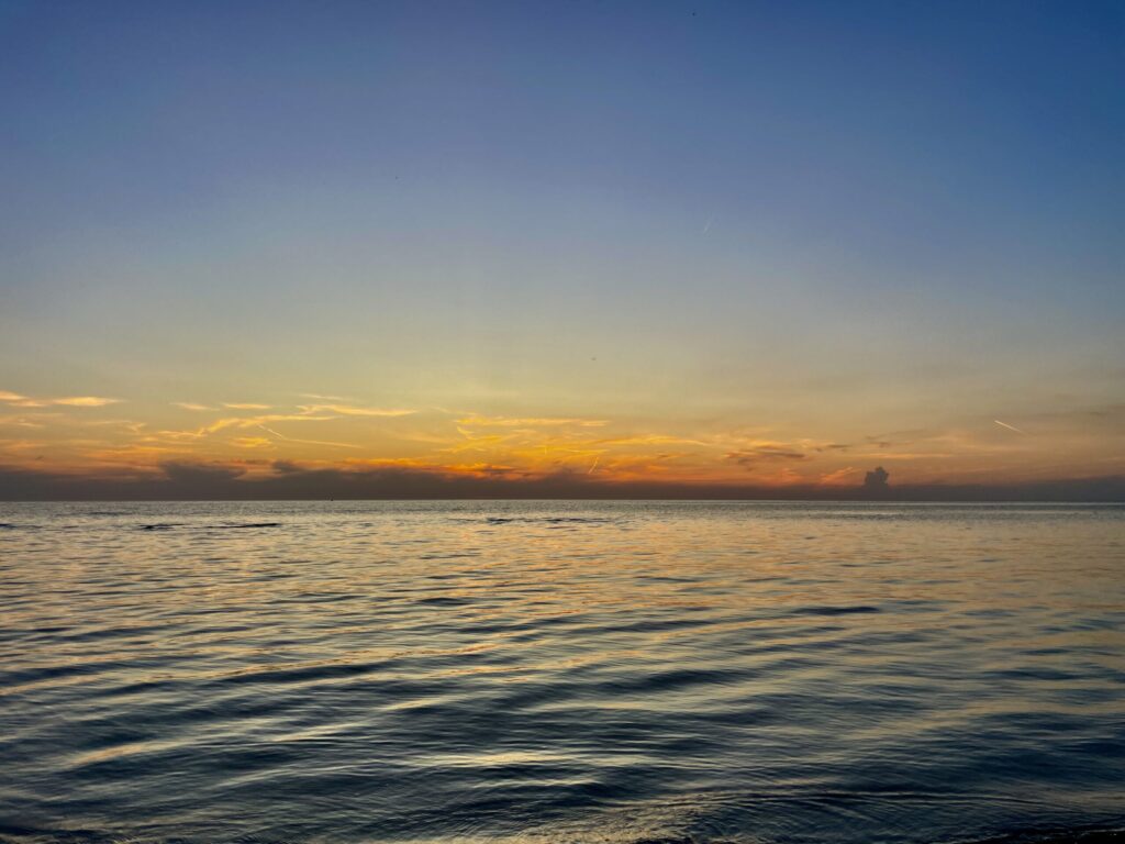 Calm Manitoba lake at sunset with golden and orange light reflecting on the water under a blue sky