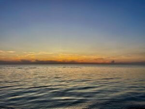 Calm Manitoba lake at sunset with golden and orange light reflecting on the water under a blue sky