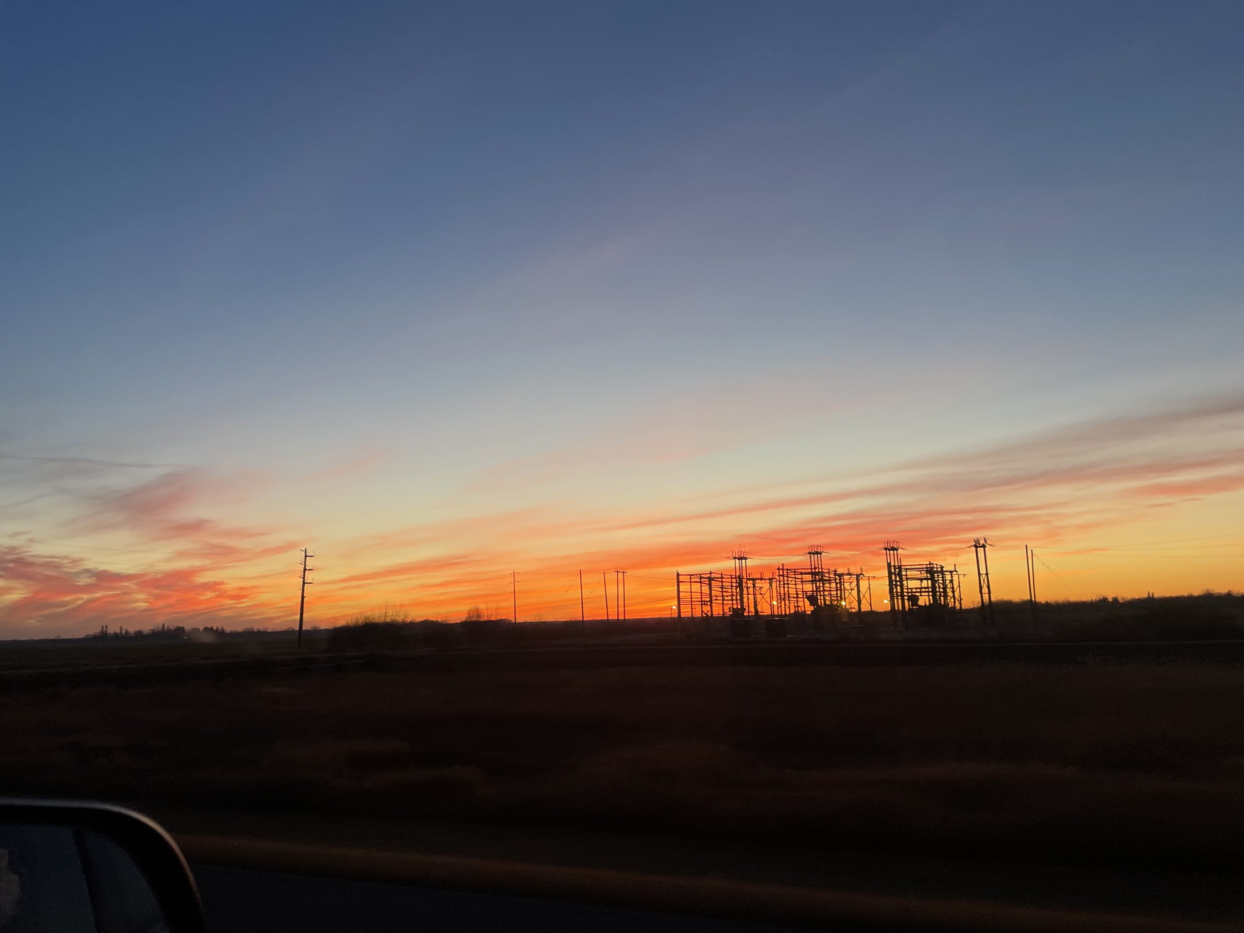 Sunset over a power substation with a vibrant orange and pink sky