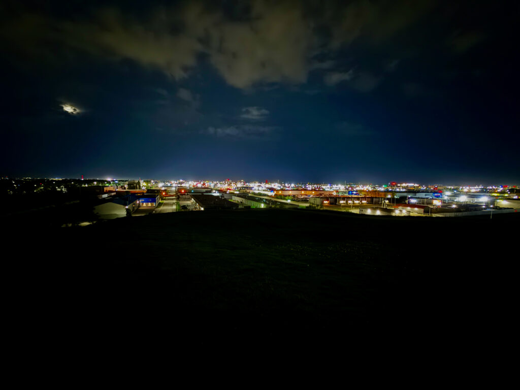 Westview Off-Leash Dog Park: Winnipeg's "Garbage Hill" and the First Park We Ever Walked in Canada 7 Panoramic view of a city at night, with lights twinkling in the distance under a cloudy sky