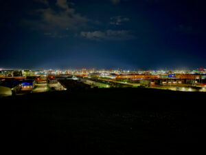 Westview Off-Leash Dog Park: Winnipeg's "Garbage Hill" and the First Park We Ever Walked in Canada 16 View of an industrial area at night, with lights from buildings and streetlamps illuminating the scene under a cloudy sky