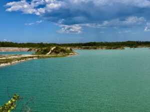 Turquoise lagoon with white limestone shores, dense green forest, and blue sky with white clouds