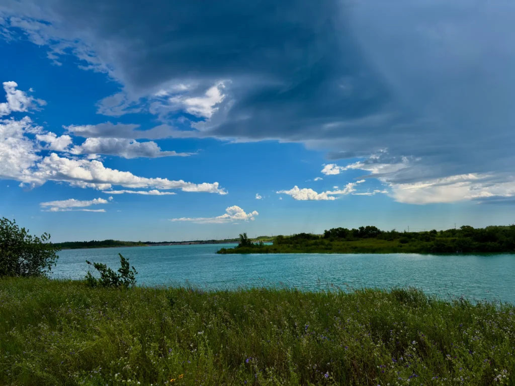 Turquoise lagoon with green vegetation along the shoreline and blue sky with white clouds overhead