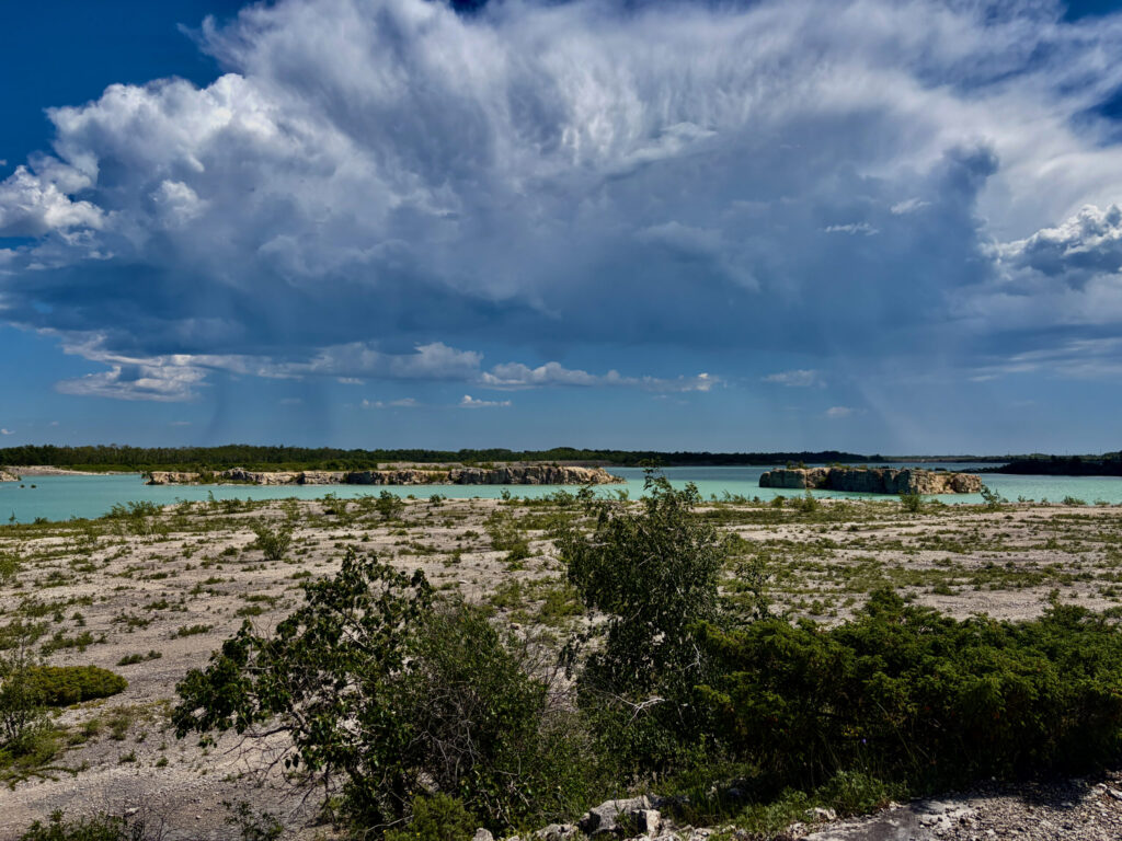 Turquoise lagoon with limestone islands and rocky foreground under a blue sky with white clouds