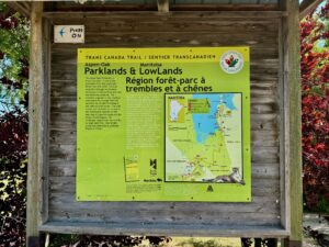 Trans Canada Trail interpretive sign for Aspen-Oak Parklands and Manitoba Lowlands, featuring bilingual text describing the landscape and a map showing the trail route, parks, and regional features between Lake Winnipeg and the Boreal Shield